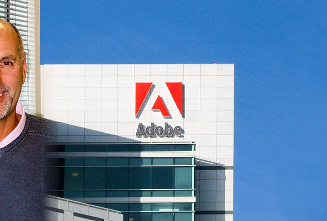 A person smiling in a headshot beside a section of a building with the Adobe logo, against a clear blue sky.