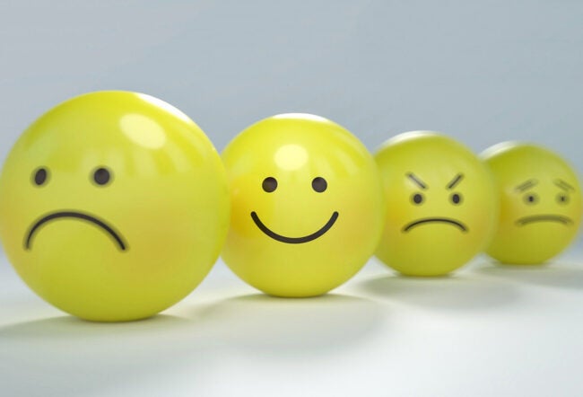 Four yellow spheres displaying various facial expressions: sad, happy, angry, and concerned, representing different emotions.