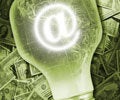A light bulb containing an email symbol is placed on top of a pile of U.S. dollar bills, symbolizing online business or e-commerce innovation.