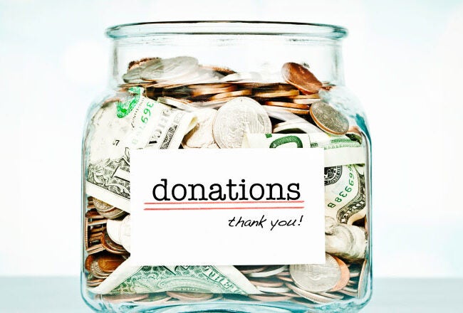 A glass jar filled with coins and dollar bills labeled "donations thank you," symbolizing a fundraising or charitable contribution.