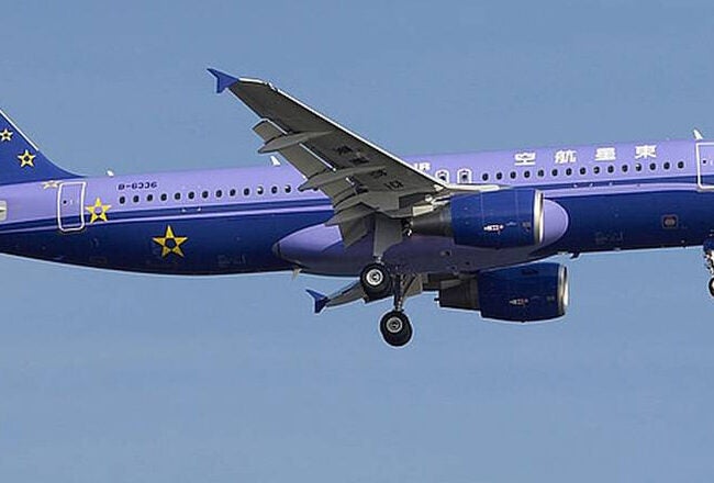A commercial airplane in flight with a purple and blue livery featuring stars and text, marked with the name "East Star."