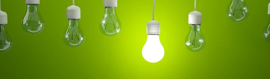 Several light bulbs hang against a green background; one bulb is illuminated, symbolizing ideas or innovation.