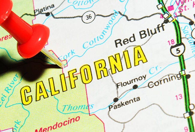 A close-up of a map showing the state of California with a red pushpin marking a location. The map details include cities, highways, and geographical features.