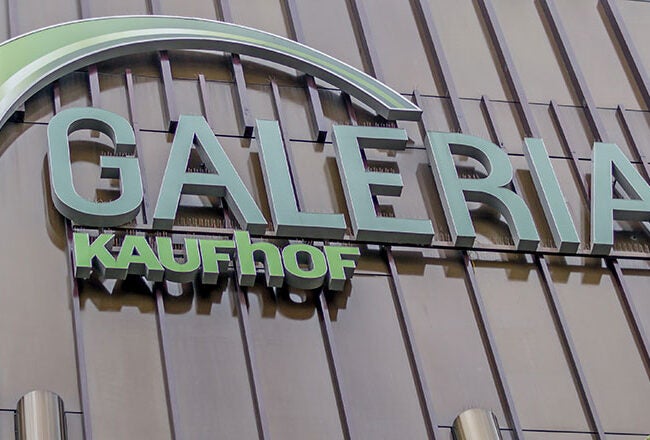 Sign for "Galeria Kaufhof" on the exterior of a building, featuring large, bold lettering and a stylized arch design.