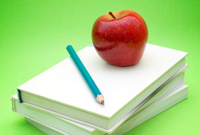 A red apple and a blue pencil rest on top of three stacked white books against a vibrant green background, symbolizing education.