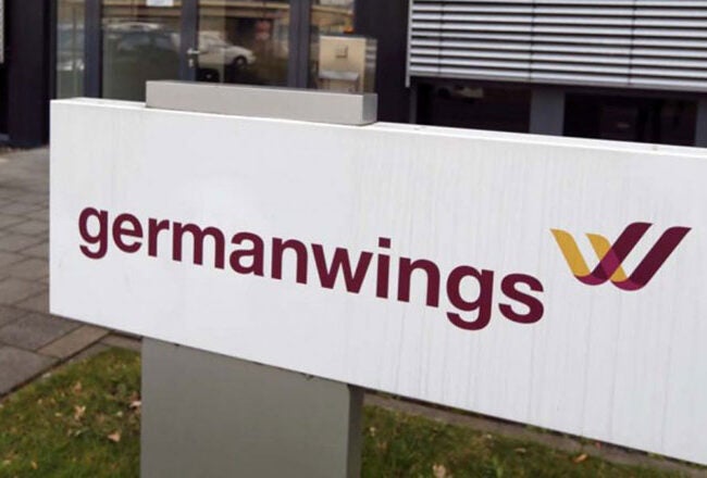 A sign displaying the logo and name of Germanwings, an airline, placed outside a modern building.