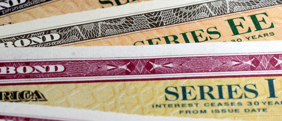 Close-up view of U.S. savings bonds, specifically Series EE and Series I, featuring intricate patterns and text detailing.