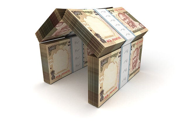 Stacks of Indian currency notes arranged to form a shape resembling a house, symbolizing investment or real estate finance.