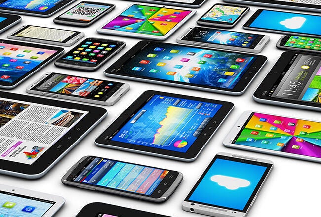 Multiple smartphones and tablets with colorful screens displaying apps, weather, news, and icons. Represents digital technology and connectivity.