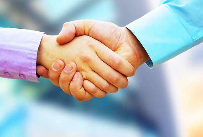 Two individuals shaking hands, symbolizing agreement or partnership. The background is blurred, suggesting a business or professional setting.