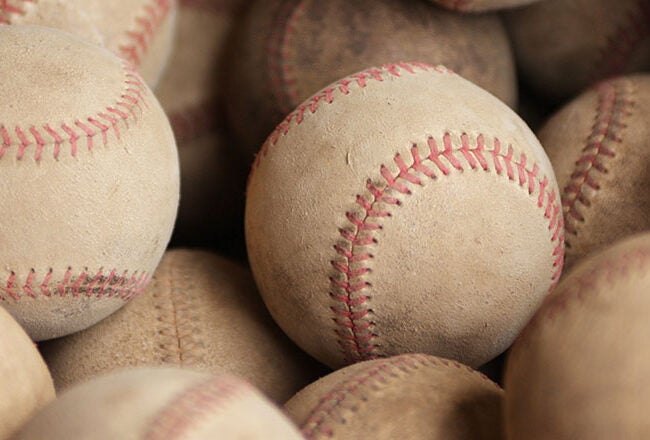 A pile of well-used baseballs with red stitching, showing signs of wear and dirt.