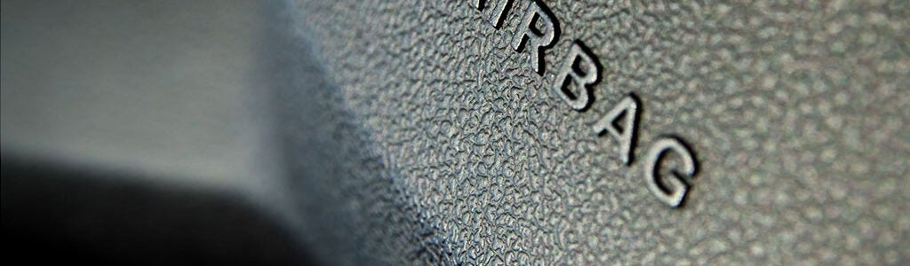 Close-up of a textured car dashboard with the word "AIRBAG" embossed, indicating the location of a vehicle''s airbag.