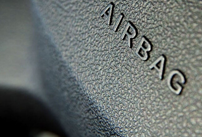 Close-up of a textured car dashboard with the word "AIRBAG" embossed, indicating the location of a vehicle's airbag.