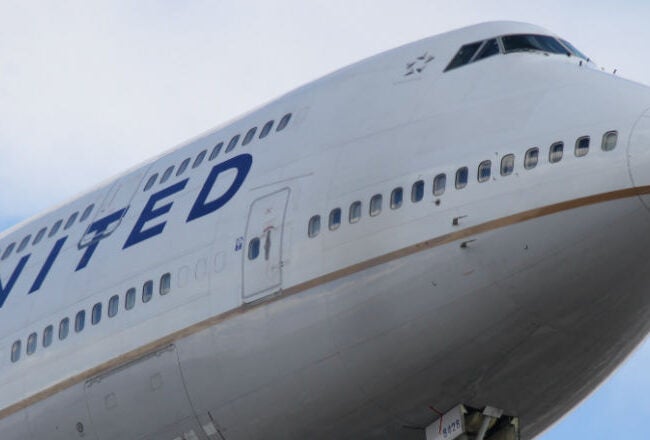A close-up view of the front of a United Airlines Boeing 747-400 aircraft against a cloudy sky.