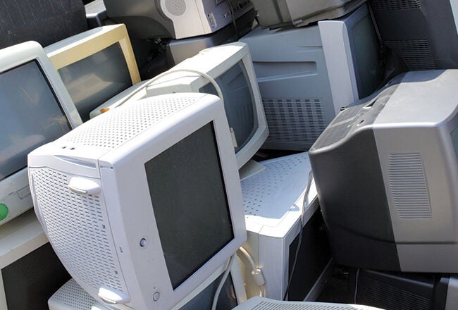 A pile of discarded CRT monitors and televisions, representing electronic waste.