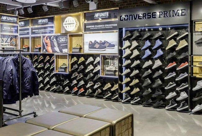 Interior of a shoe store featuring racks of various sneakers, including Converse and Vans, along with clothing on display.