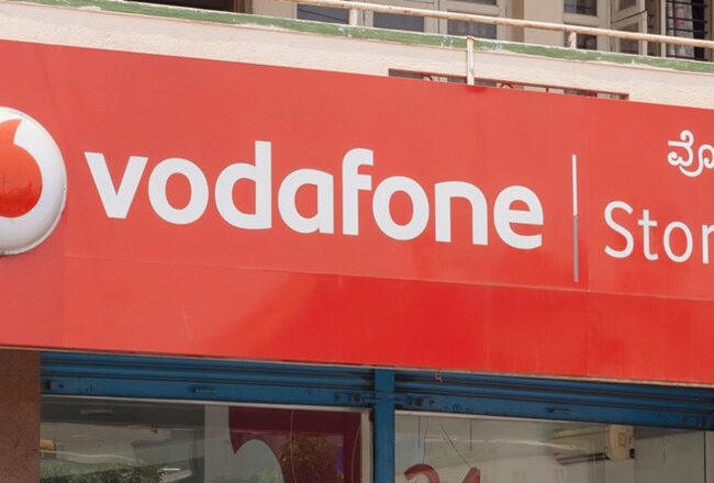 A Vodafone store sign with the Vodafone logo and text in English and another language on a red background.