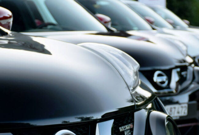 A row of black cars parked closely together, featuring shiny exteriors and visible Nissan emblems, possibly representing a dealership or showroom.