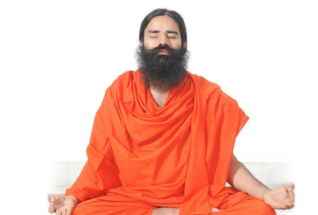 A person in orange robes meditating with eyes closed, representing peace and mindfulness.