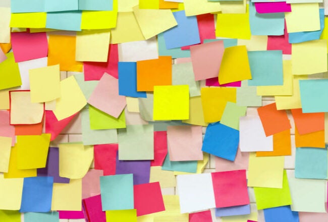 A colorful assortment of sticky notes overlapping each other, creating a vibrant, chaotic pattern.