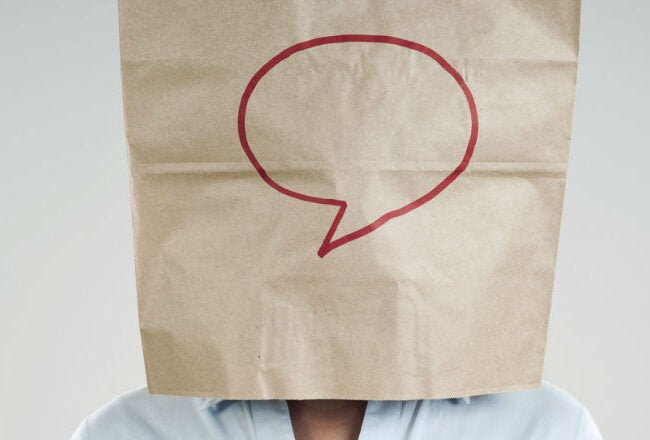 A person wearing a paper bag on their head with a red speech bubble drawn on it.