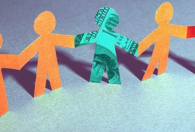 A row of paper cutouts shaped like human figures holding hands, with one figure made from a dollar bill among orange figures. This represents economic concepts affecting groups.