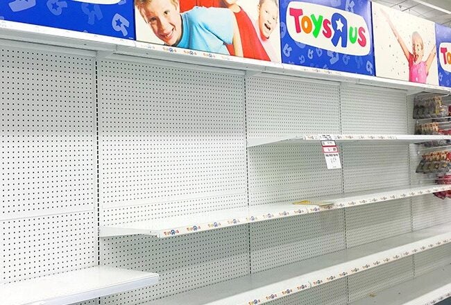 Empty store shelves under a Toys"R"Us sign, indicating a clearance or store closure sale.