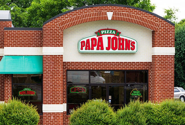 A Papa John''s Pizza restaurant with red brick exterior, a green awning, and signage displaying "Papa John''s" in red and green.