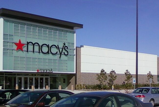 A Macy''s department store with a large sign featuring a red star logo and the name "Macy''s". The building has a modern exterior with a parking lot in front.