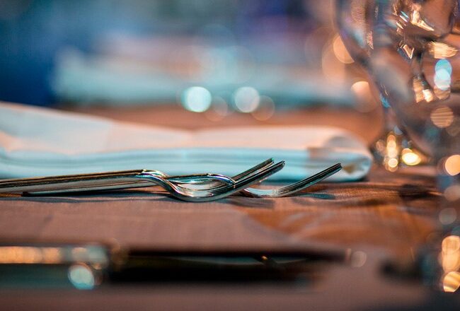 Elegant table setting with folded napkins, silverware, and glassware, suggesting a formal dining or event atmosphere.