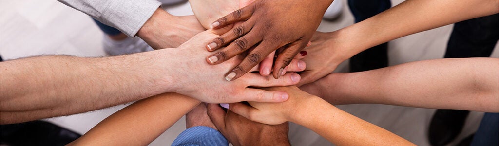 A diverse group of hands stacked together, symbolizing teamwork, unity, and cooperation.