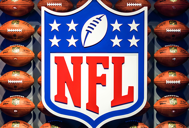 The image shows the NFL logo against a background of numerous American footballs.