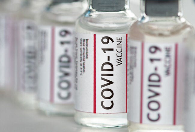 Rows of COVID-19 vaccine vials, each labeled with "COVID-19 Vaccine," symbolizing immunization efforts.