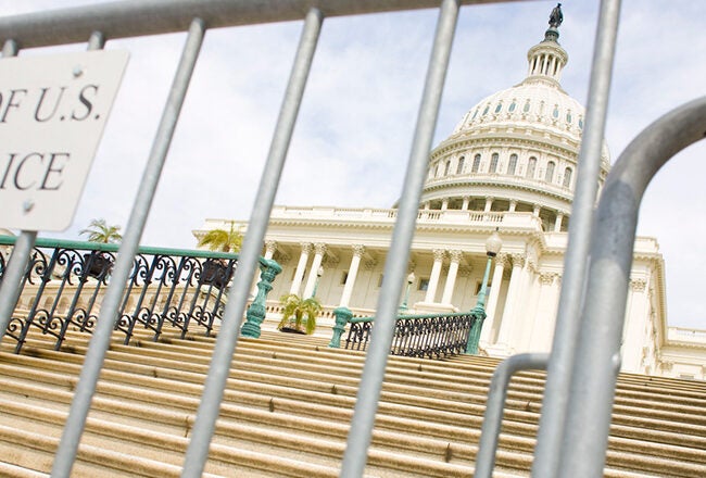 The image shows the U.S. Capitol building with a metal barrier in the foreground sporting a sign that reads "Property of U.S. Capitol Police."