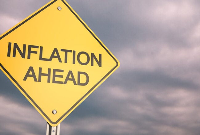 A yellow caution sign with the words "Inflation Ahead" against a cloudy sky, symbolizing economic concerns.