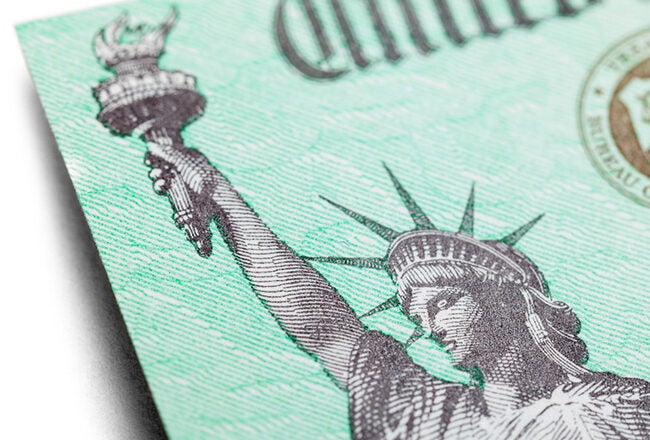 Close-up of a U.S. Treasury check, featuring part of a background with the Statue of Liberty and text elements.