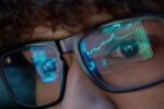 Young Business Man Looking At Trading Charts Reflecting In Glasses, Close Up.