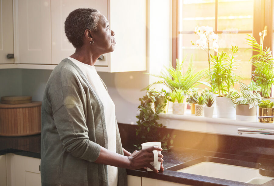 Older woman staring out the window to illustrate racial wealth gap for retirees
