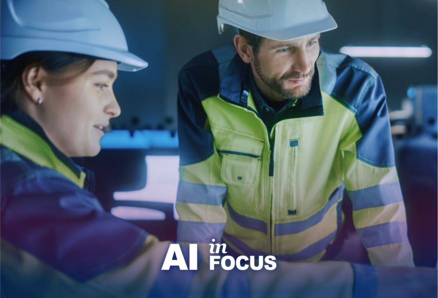 Project engineers in uniform pointing at a screen discussing how AI transforms industries and organizations with a text overlay that reads "AI in Focus"