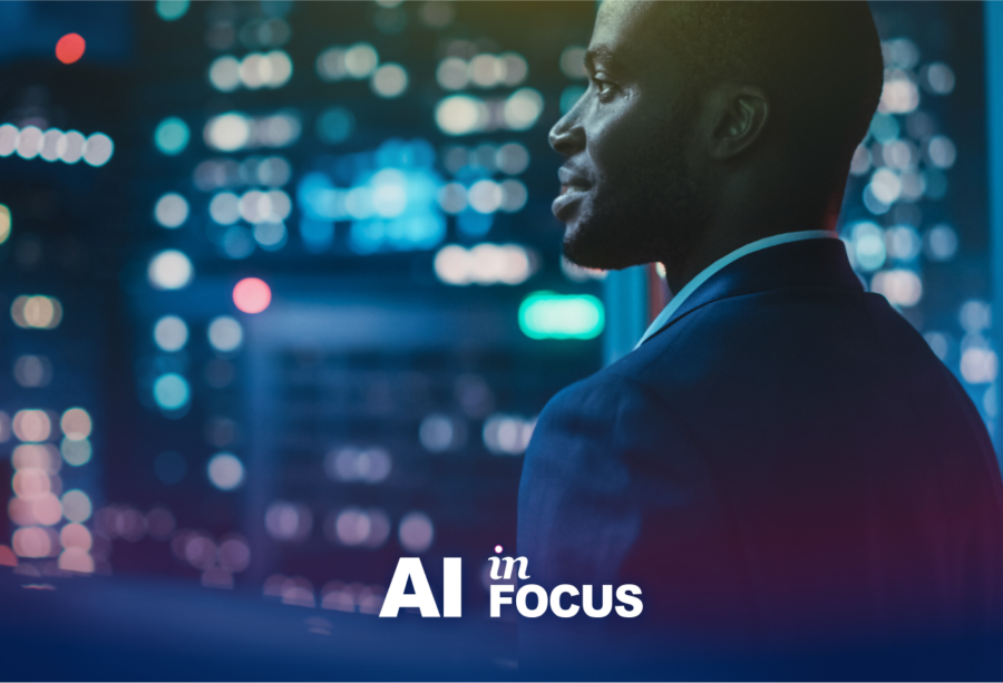 Businessman thinking about the future of AI as he looks hopefully at a cityscape with a text overlay that reads "AI in Focus"