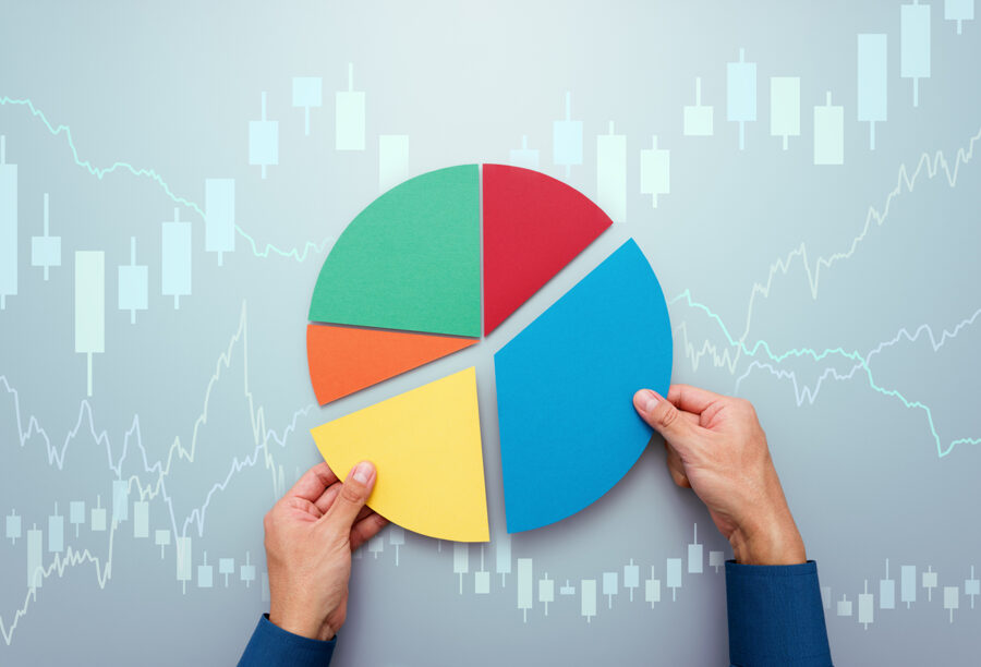 Hands putting pieces of a pie chart together over background graphics of stocks to show diversified investments for retirement