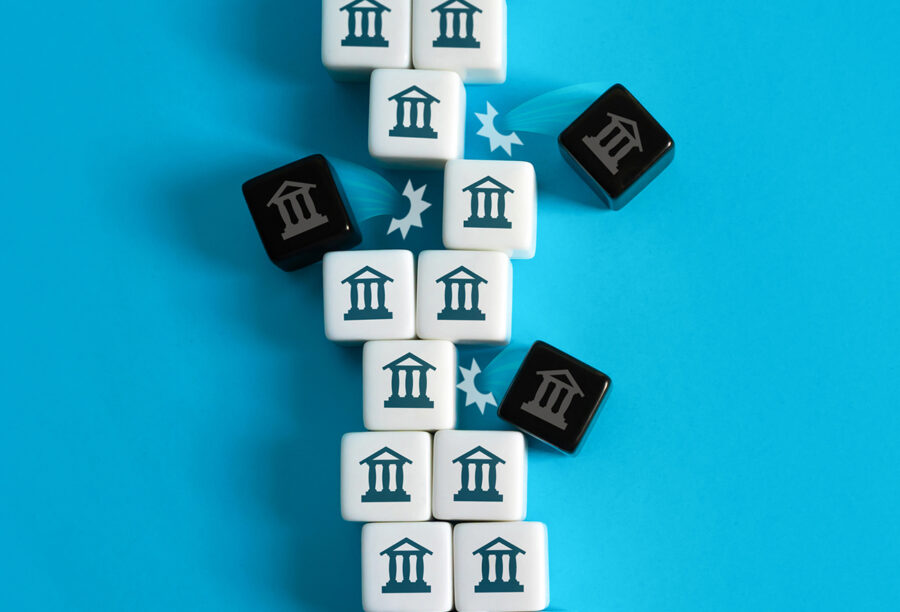 A stack of blocks with bank icons on them with some of the blocks jumping off to symbolize bank failures and establishing financial stability