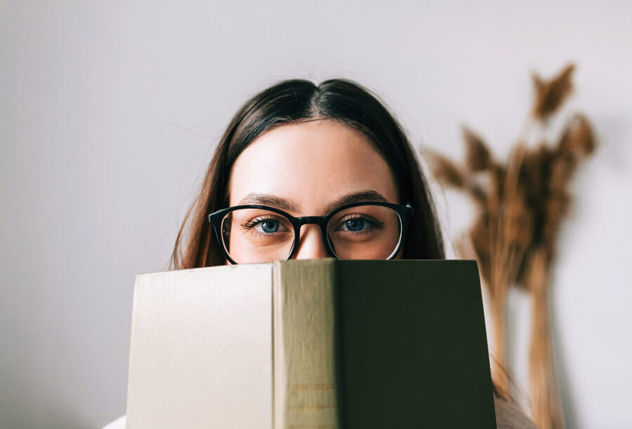 Woman peering over an open book to show how imagining yourself as the hero of your own story can help you live a meaningful life