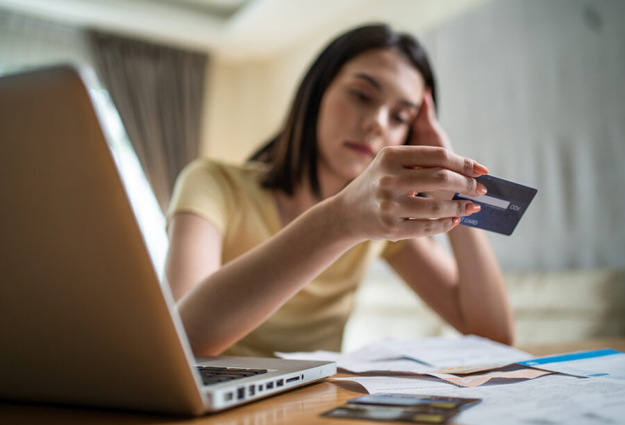 Woman sitting at a desk staring at her credit card in her hand