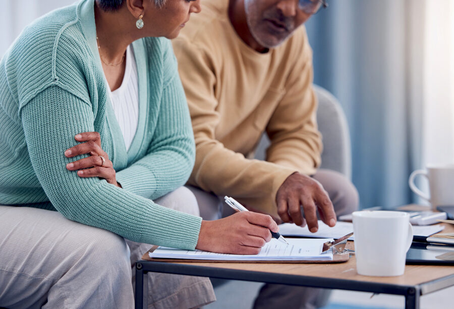 An elderly couple sitting at a coffee table reviewing their financial documents and retirement plans