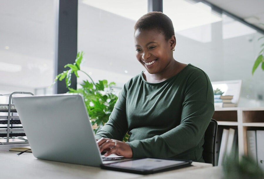 Successful Black woman smiling as she works in her office on her laptop