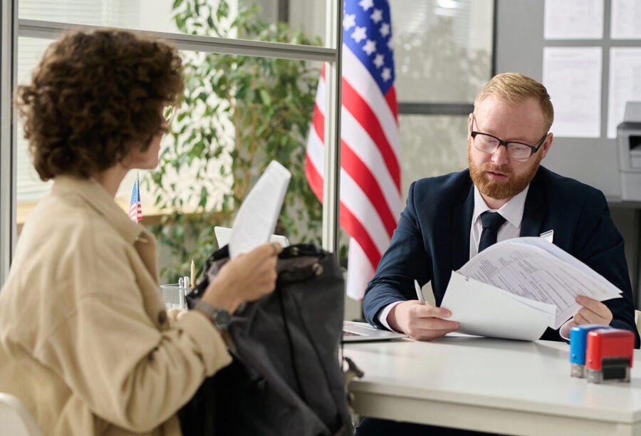 A male worker revising documents of young woman applying for visa in US immigration office