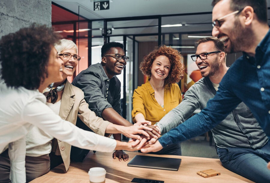 Group of coworkers putting their hands together and smiling after making a good decision