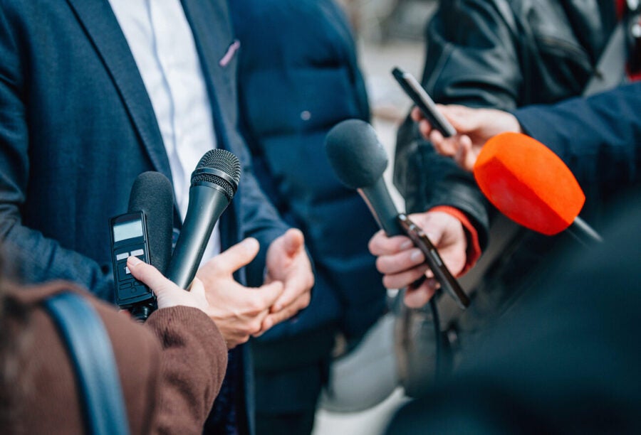 Journalists holding microphones out to a politician to illustrate the issue of media bias