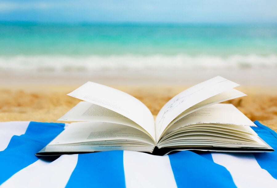 A book flipped open on a blanket at the beach